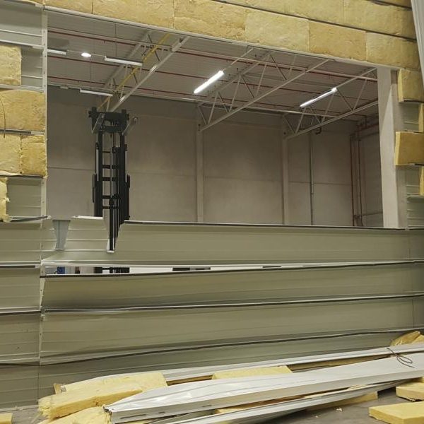 Blick durch ein großes Fenster in einem Lagerhaus mit gestapelten Platten.