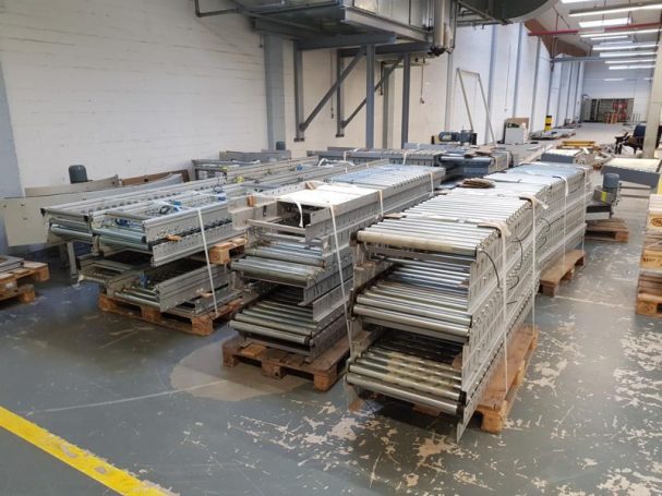 Gestapelte Metallplatten auf Holzpaletten in einer Lagerhalle.