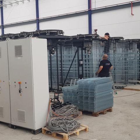 Arbeiter montieren technische Ausrüstung in einer Lagerhalle. Paletten mit Glas liegen bereit.