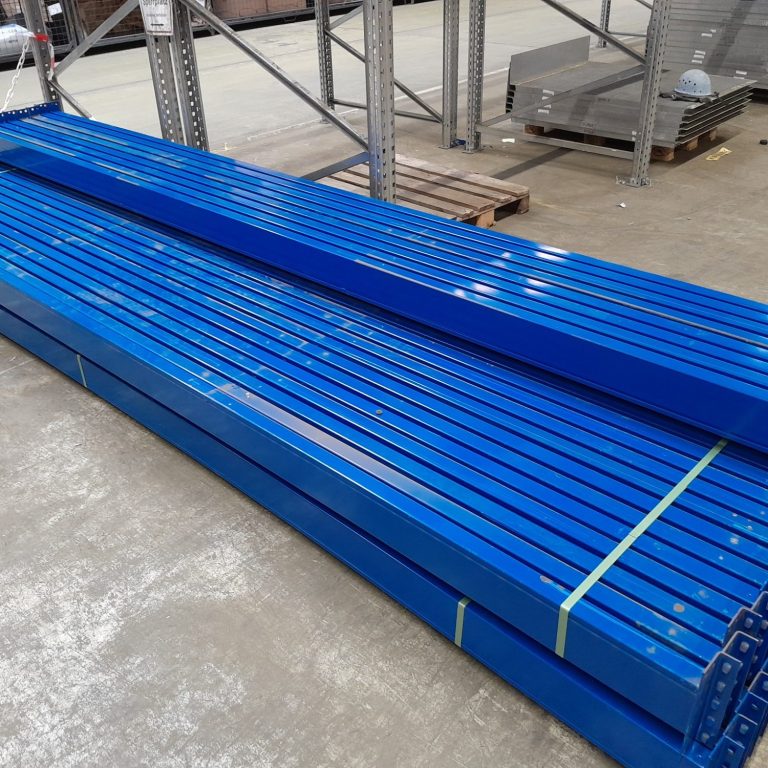 Blaue Metallstangen liegen gestapelt auf einem Lagerboden.