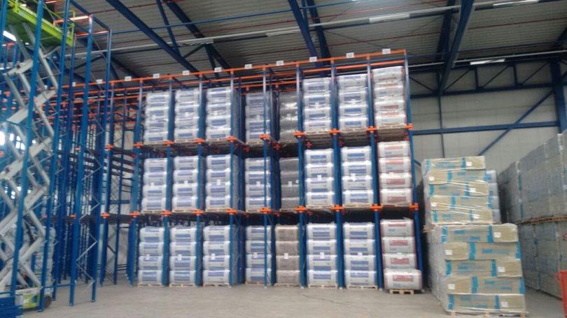 Lagerregale mit gestapelten Kisten und Paletten in einer großen Lagerhalle.