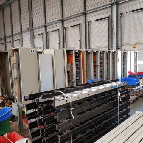 Lagerraum mit Regalen, Stapeln von Metallplatten und verschiedenen Behältern.