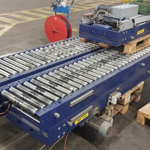 Förderband mit Rollen auf Paletten im Industrieumfeld.