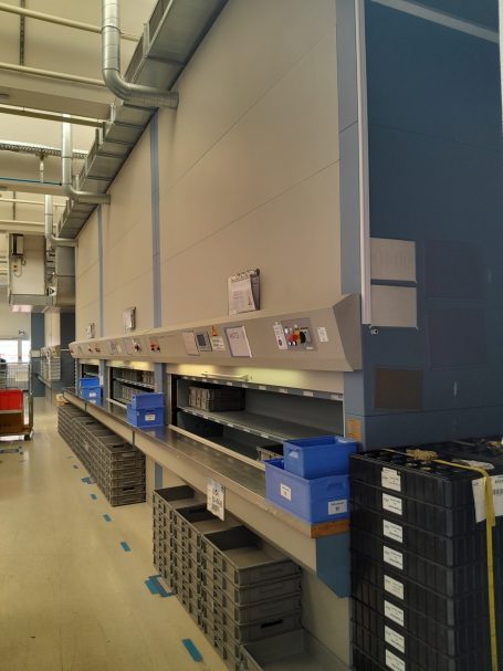 Hochregale mit blauen und schwarzen Behältern in einer Lagerumgebung.