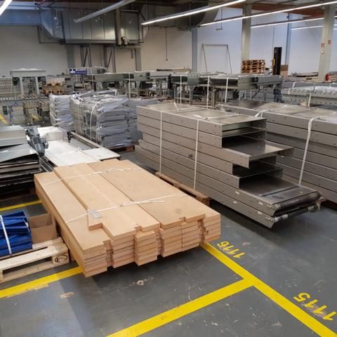 Lager mit Holzplatten und gestapeltem Metallmaterial in großem Raum.