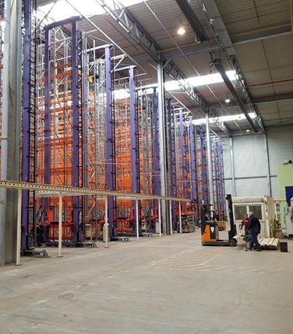 Lagerhalle mit hohen Regalen und einem Gabelstapler in Betrieb.