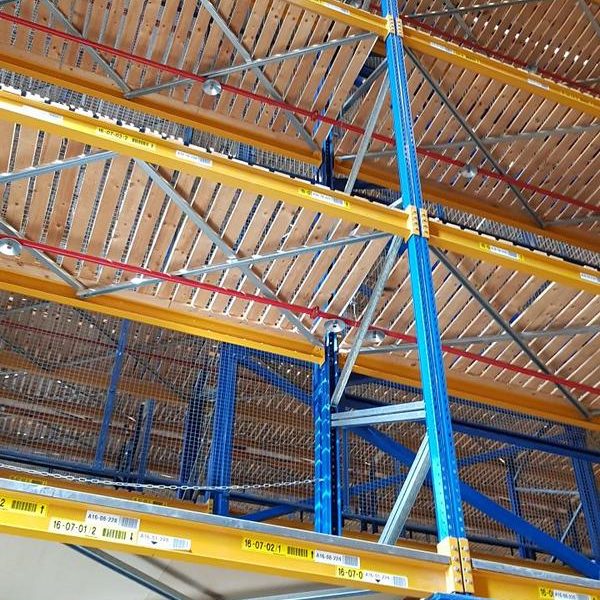 Blick auf ein Regalsystem aus Metall mit blauen und gelben Stützen und Holzplatten.