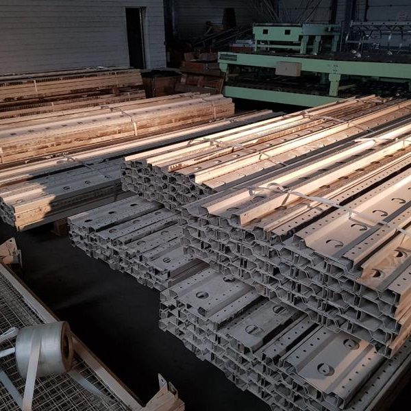 Gestapelte Metallrahmen in einem Lager, teilweise beleuchtet.