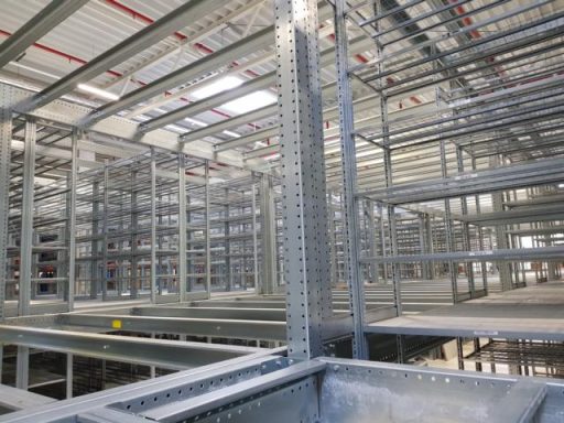 Innenansicht eines modernen Lagerhauses mit Metallregalen und strukturierten Ständern.