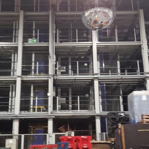 Lagerregale mit mehreren Ebenen, Maschinen und Werkzeugen im Vordergrund.