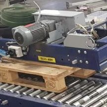 Eine Maschinenkomponente auf einer Holzpalette, umgeben von Förderrohren.