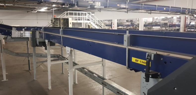 Blaue Förderbandanlage in einem geräumigen, lichtdurchfluteten Industrieumfeld.
