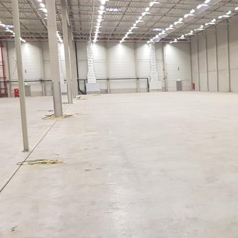Großer, leerer Lagerraum mit betontem Betonboden und Deckenbeleuchtung.
