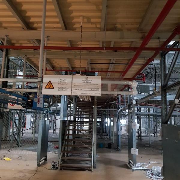 Blick auf eine Baustelle mit Treppe, Gerüsten und Sicherungshinweisen.