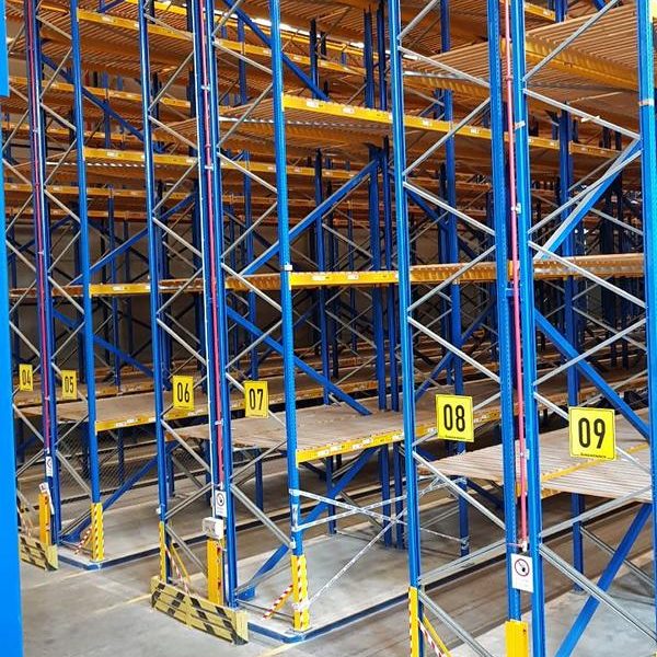 Lagereinrichtung mit blauen und gelben Regalen sowie Nummern auf den Regalböden.