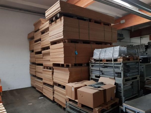 Lager mit gestapelten Holzpaletten und Kartons auf dem Boden.