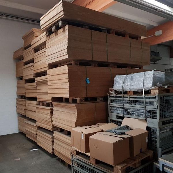 Stapeln von Holzplatten und Kartons in einem Lagerraum.