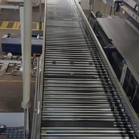 Förderband in einer industriellen Umgebung, mit mehreren Rollen und einem glatten Verlauf.