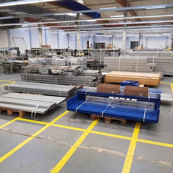 Lagerraum mit gestapelten Metallregalen und Holzbrettern auf Paletten.