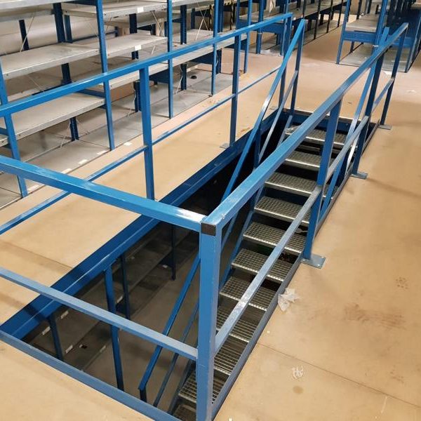 Eingang zu einer Treppe mit blauen Geländern in einem Innenbereich.