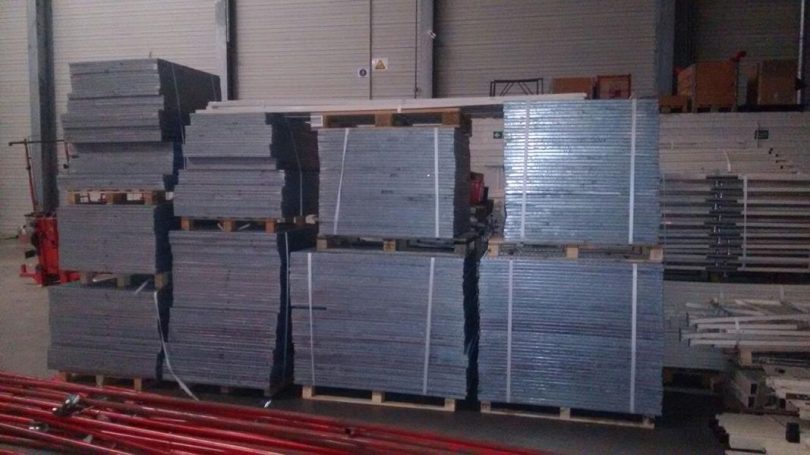 Gestapelte graue Platten auf Holzpaletten in einem Lagerraum.