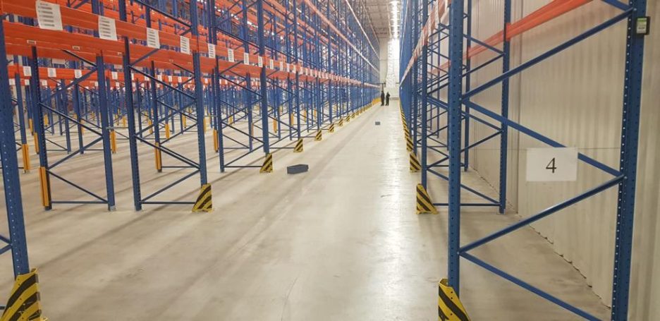 Ein leerer Lagerraum mit hohen Regalen und einem klaren, begehbaren Gang.