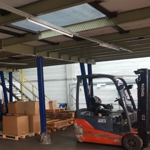 Gabelstapler in einem Lager mit Kisten und Regalen im Hintergrund.