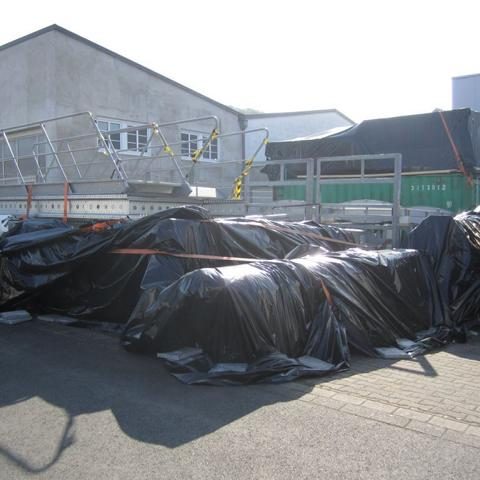 Schwarze Planen bedecken Stapel von Materialien auf einer Baustelle.