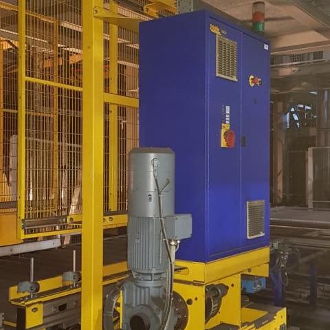 Blaue Steuerungseinheit auf gelber Plattform in einer Industrieumgebung.