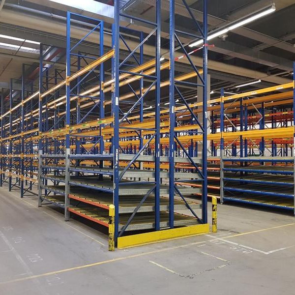 Leere Regale in einem Lager mit blauen und gelben Gestellen auf einem Betonboden.