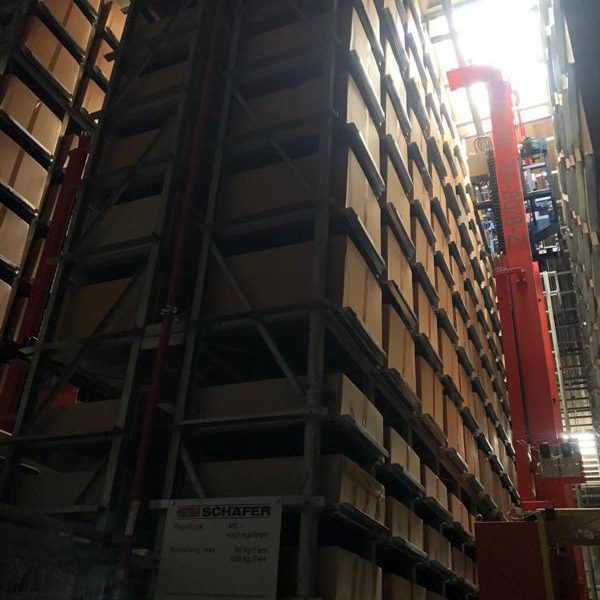 Hochregallager mit Regalen voller Kisten und einem roten Fördergerät.