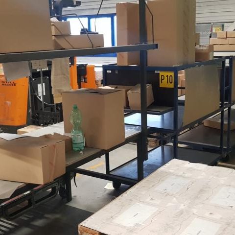 Lagerregal mit Kartons und einem Tisch, umgeben von weiteren Paketen.