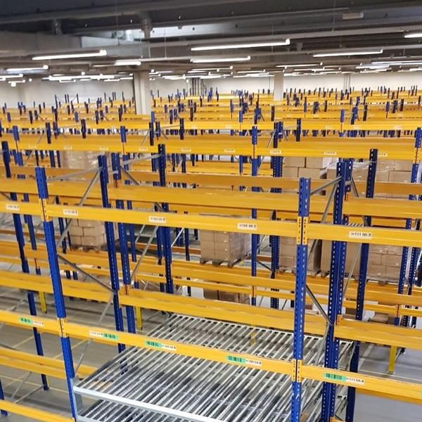 Leere Lagerregale mit blauen und gelben Gestellen in einem großen, hellen Raum.