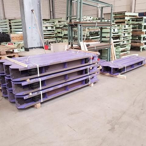 Stapel von lila Paletten in einem Lager mit weiteren Materialien im Hintergrund.