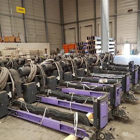 Mehrere lila Hebevorrichtungen mit Kabeln in einem Lagerraum angeordnet.