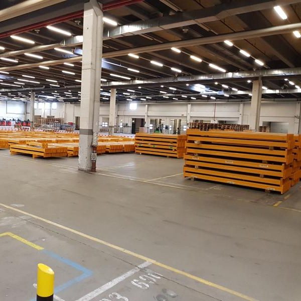 Lagerhalle mit gestapelten orangefarbenen Paletten auf dem Boden.