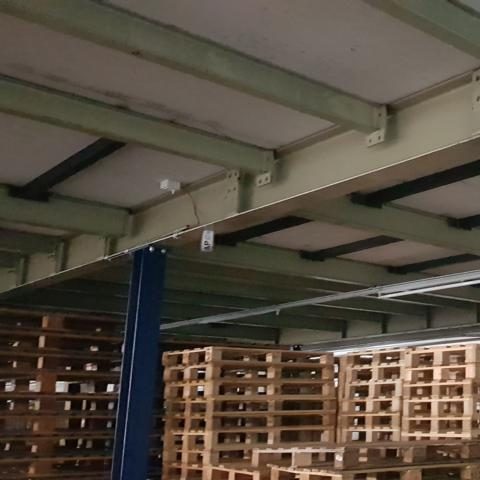 Lagerraum mit gestapelten Holzpaletten und einem sichtbaren Tragwerk.