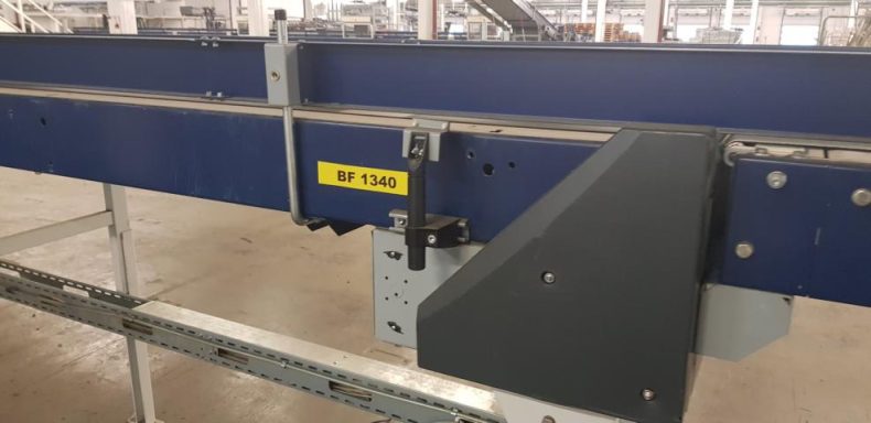 Nahaufnahme eines Förderbands mit Metallrahmen und mechanischen Komponenten.