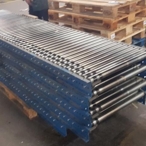 Gestapelte Metallrohre auf Holzpaletten in einer Lagerumgebung.