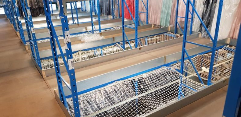 Regalstruktur mit blauen Metallschienen und leeren Ablagen in einem Lagerraum.
