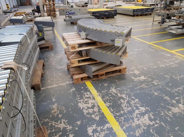 Paletten mit großen, grauen Bauteilen in einer Industriehalle.