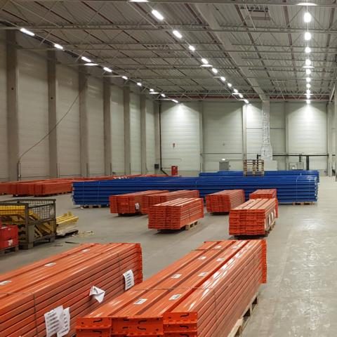Lagerhalle mit orangefarbenen und blauen Paletten in geräumiger Umgebung.