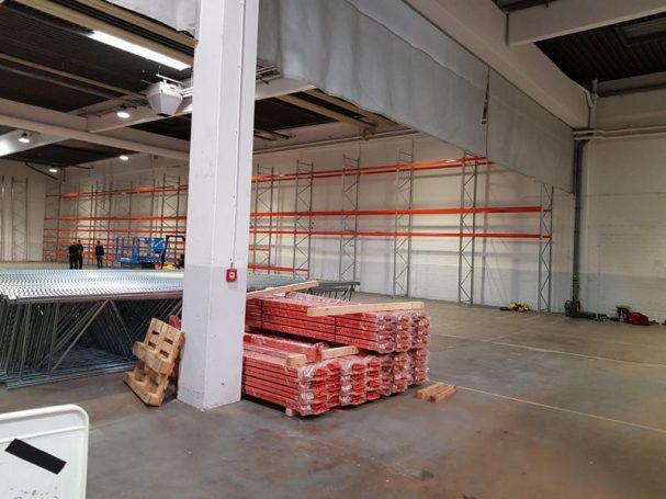 Lagerraum mit gestapelten Ziegeln und sichtbaren Regalen im Hintergrund.