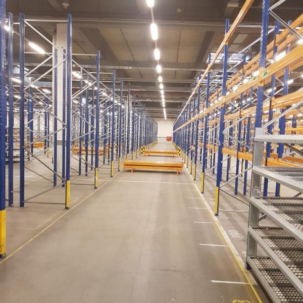 Leeres Lagerhaus mit hohen Regalen und breiten Gängen zwischen den Regalen.