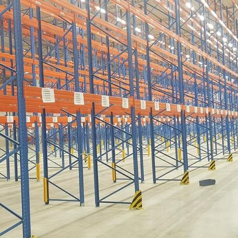 Lagereinrichtungen mit blauen und orangen Regalen in einem großen, leeren Raum.