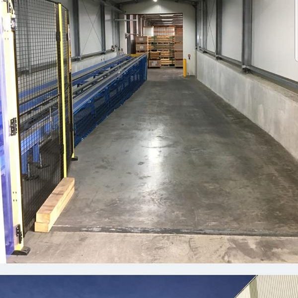 Ein langer, gerader Gang mit einem blauen Tisch an der linken Wand und grauem Boden.