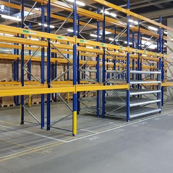 Regalsystem in einem Lager mit blauen und gelben Regalböden und leerem Boden.