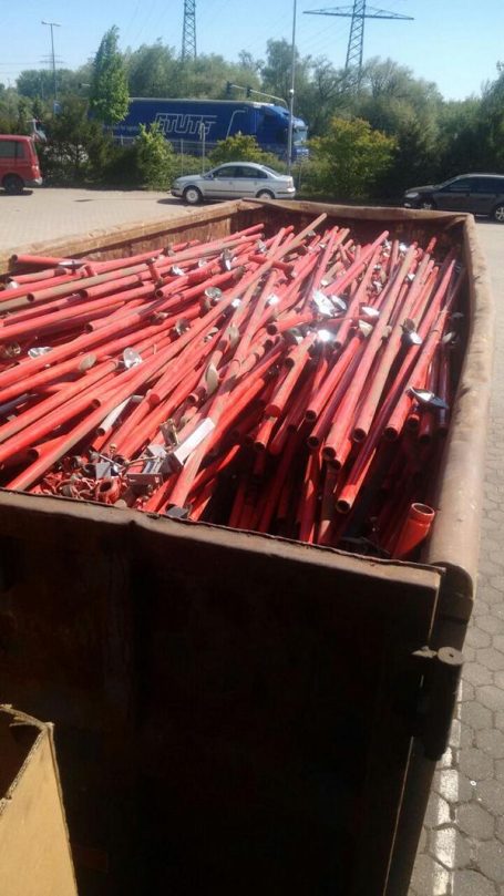 Rote Metallstangen in einem Container, umgeben von Industrie- und Verkehrsbereich.