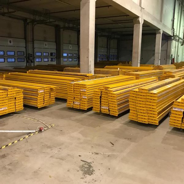 Gelbe Metallstangen in einem großen Lagerraum, ordentlich gestapelt.