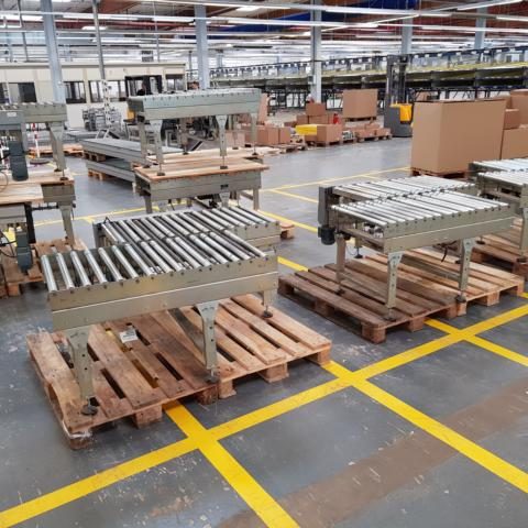 Regal und Paletten in einer Lagerhalle, mit Förderbändern auf Holzpaletten.